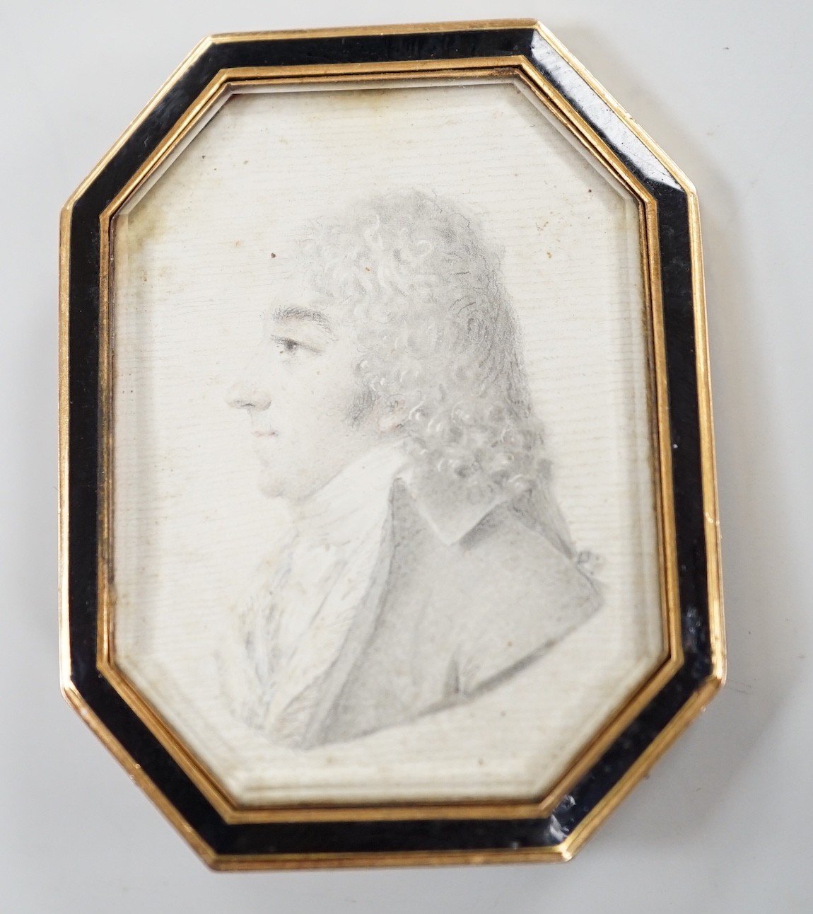 A Regency yellow metal and black enamel framed brooch (pin missing), with inset miniature pencil portrait of a bust of a gentleman to dexter, 51mm.